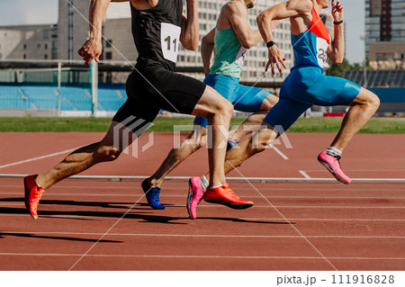 group male athletes sprinting on red track stadium, muscles taut, competing fiercely. summer sports games 111916828