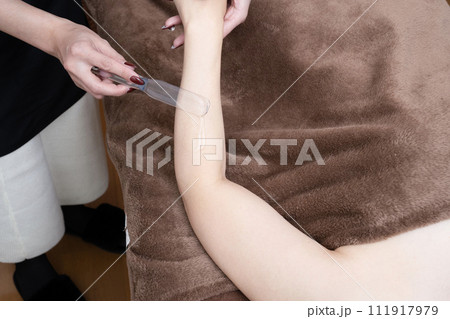 脱毛の施術を受ける女性の腕にジェルを塗る女性 脱毛の施術を受ける女性の腕にジェルを塗る女性 111917979