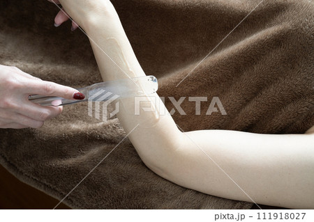 脱毛の施術を受ける女性の腕にジェルを塗る女性 脱毛の施術を受ける女性の腕にジェルを塗る女性 111918027
