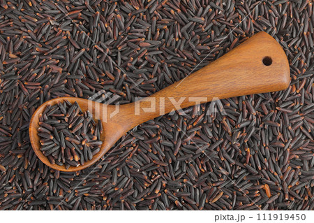Black rice in a wooden spoon as a background. Top view. Flat lay Black rice in a wooden spoon as a background. Top view. Flat lay 111919450