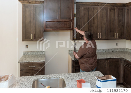 Level measurement tool is used by supervisor during assembly of new kitchen cabinets 111922170