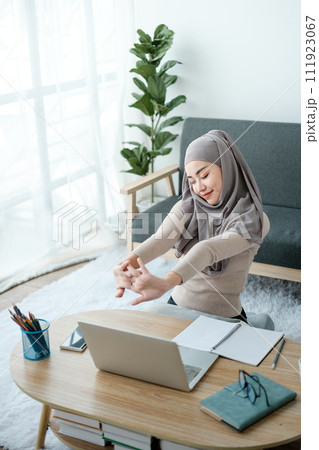 Young business Asian Business muslim woman in hijab using a tablet, Sitting near the window in the living room.  111923067