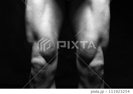 bodybuilders legs. Naked muscular male part in the Dark 111923254