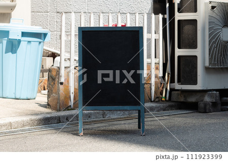 Blank white outdoor advertising stand/sandwich board mock up template. Clear street signage board placed by an outdoor dinning area of a restaurant. Background texture of standee on street. Blank white outdoor advertising stand/sandwich board mock up template. Clear street signage board placed by an outdoor dinning area of a restaurant. Background texture of standee on street. 111923399