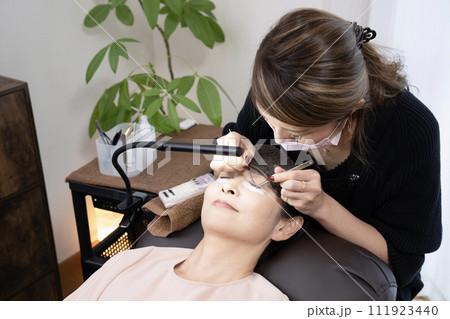 まつ毛エクステの施術を受ける女性（撮影協力　マカナニ) 111923440