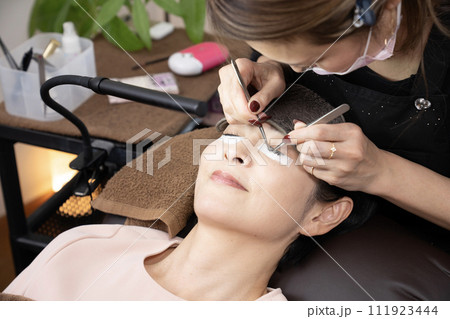 まつ毛エクステの施術を受ける女性（撮影協力　マカナニ) 111923444