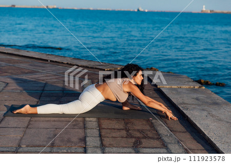 Woman doing yoga asana breathing practice on the beach by the sea 111923578