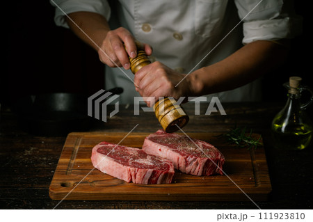 chef seasoning steak with salt and pepper chef seasoning steak with salt and pepper 111923810