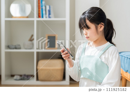 リビングでスマホを操作する小学生の女の子。 111925182