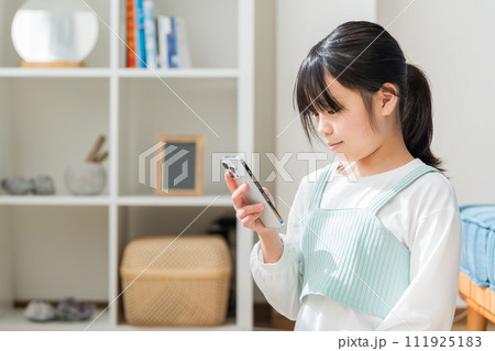 リビングでスマホを操作する小学生の女の子。 111925183