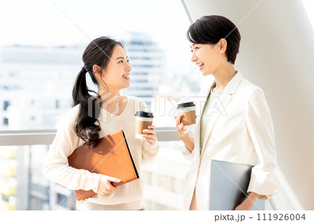 コーヒー片手に談笑するビジネスウーマン 111926004