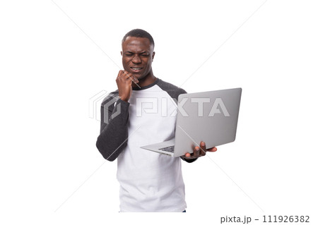 young american man dressed in a black and white sweater holding a gray laptop on a white background 111926382
