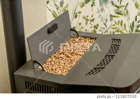 Horizontal image of a pellet stove with a full hopper, sustainable heat. Green energy concept. 111927310