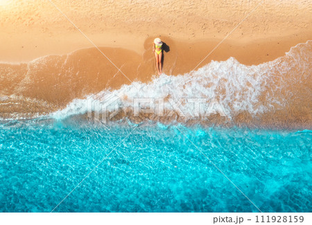 Aerial view of woman on sandy beach and blue sea with waves Aerial view of woman on sandy beach and blue sea with waves 111928159