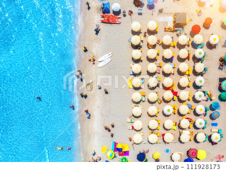 Aerial view of colorful umbrellas on sandy beach and blue sea Aerial view of colorful umbrellas on sandy beach and blue sea 111928173