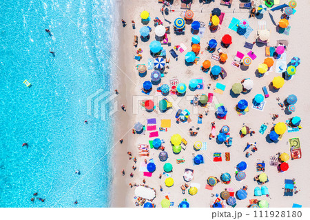 Aerial view of colorful umbrellas on beach, people in blue sea 111928180