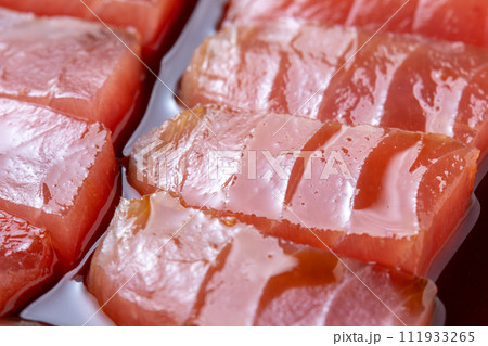 漬けまぐろ調理シーン。マグロ切り身を漬けだれに漬ける。 漬けまぐろ調理シーン。マグロ切り身を漬けだれに漬ける。 111933265