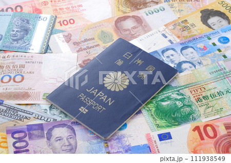 日本のパスポート(一般旅券5年用紺色)と、さまざまな国の通貨の紙幣で、海外旅行のイメージ 日本のパスポート(一般旅券5年用紺色)と、さまざまな国の通貨の紙幣で、海外旅行のイメージ 111938549