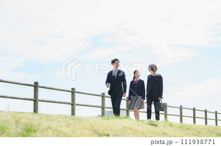 土手を歩く3人家族 111938771