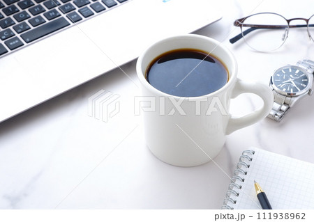 コーヒーを飲みながらノートパソコンでデスクワーク中のイメージ	 111938962