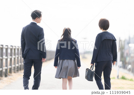 土手を歩く3人家族 111939045