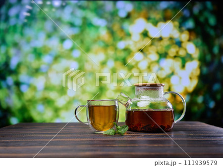 natural organic herbal tea in glass teapot and cup on a wooden table natural organic herbal tea in glass teapot and cup on a wooden table 111939579