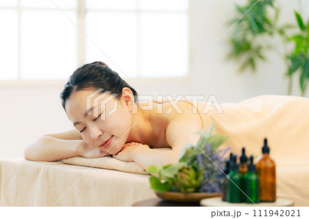 マッサージベッドに寝る女性とハーブオイルイメージ 111942021