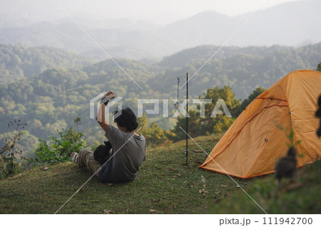 landscape and travel concept with solo freelancer man relax and play with cat and see sunset with layer of mountain landscape and travel concept with solo freelancer man relax and play with cat and see sunset with layer of mountain 111942700