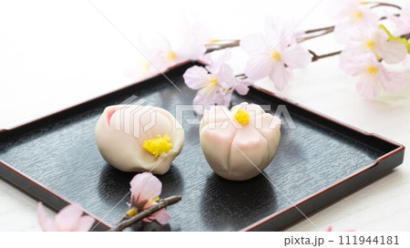 黒角皿にのった桜の花と桃の花の上生菓子 111944181