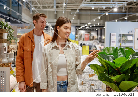 Happy man and woman couple walking through store racks with goods 111946021