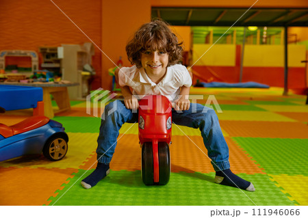 Little boy child playing at playroom riding toy motorcycle 111946066