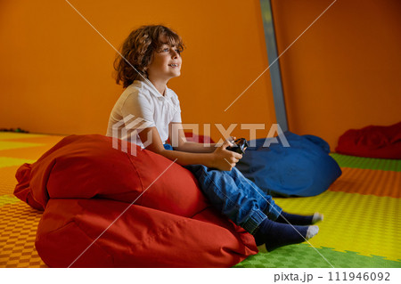 Portrait of little boy playing video game at kids center Portrait of little boy playing video game at kids center 111946092