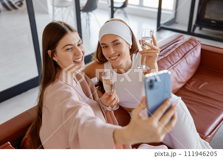 Two woman friends or sisters taking selfie photo on smartphone Two woman friends or sisters taking selfie photo on smartphone 111946205
