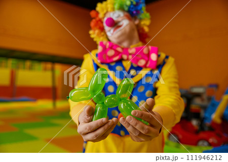Cute green balloon dog toy in hand of funny clown 111946212