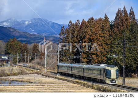 冬山を背景に走る特急リバティ 111948286