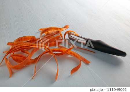 Knife for peeling vegetables and peeling carrots on a light wooden table Knife for peeling vegetables and peeling carrots on a light wooden table 111949002