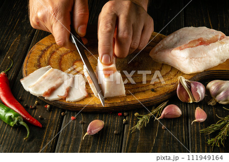 Cutting lard into small pieces for a snack in the hands of a chef with a knife. National Ukrainian food. Salo is delicious with garlic 111949164