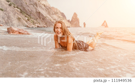 Woman summer travel sea. Happy tourist in black dress enjoy taking picture outdoors for memories. Woman traveler posing on sea beach surrounded by volcanic mountains, sharing travel adventure journey 111949536