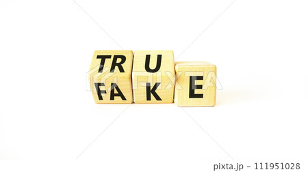 Fake or true symbol. Turned wooden cubes and changed the word fake to true or vice versa. Beautiful white table, white background, copy space. Business and fake or true concept. 111951028