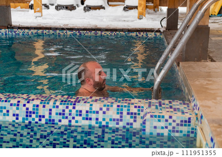 Man enjoying a leisurely swim in a snowcovered swimming pool 111951355