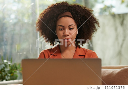 Portrait of woman watching educational video on laptop at home 111951376