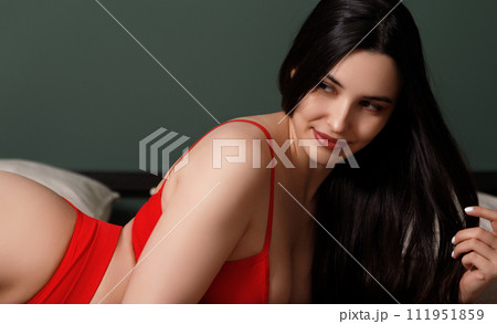 A woman with long black hair in a red bodysuit is A woman with long black hair in a red bodysuit is 111951859
