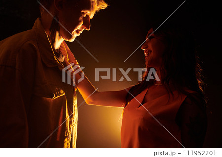 Happy young woman in love putting hand on shoulder of her boyfriend and looking in his eyes Happy young woman in love putting hand on shoulder of her boyfriend and looking in his eyes 111952201