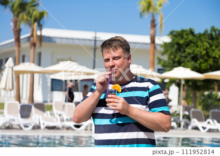 A male tourist from the USA on vacation in Turkey drinks a cocktail A male tourist from the USA on vacation in Turkey drinks a cocktail 111952814