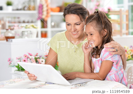 Portrait of happy mother and daughter using laptop 111954589