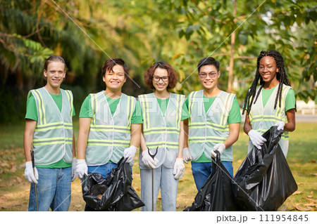 Diverse group of volunteers standing with bags of garbage they collected together 111954845