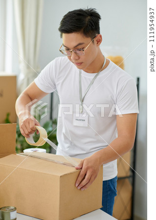 Volunteer taping box with packed goods for people in need 111954937