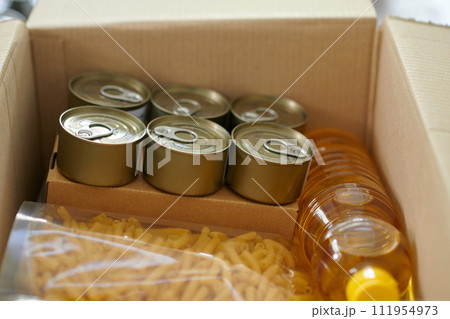 Box with canned food, vegetable oil and macaroni packed for family in need 111954973