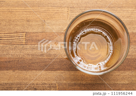 Nearly empty glass of beer on wooden table 111956244