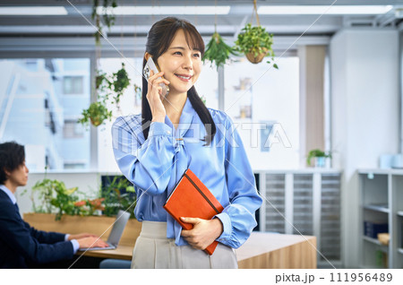 スマホで電話するビジネスカジュアルの若い女性 スマホで電話するビジネスカジュアルの若い女性 111956489